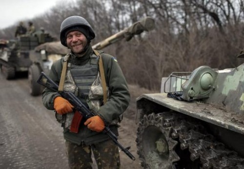 A member of the Ukrainian armed forces and armoured personnel carriers smiles as they prepare to move to pull back from Debaltseve region, near Artemivsk February 26, 2015. 