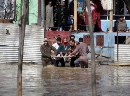 An ailing woman is carried on a wooden plank to a safer place from her partially submerged house after incessant rains in Srinagar March 30, 2015. REUTERS