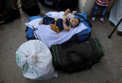 Palestinian girl lies on luggages as she waits with her family for a travel permit to cross into Egypt, at the Rafah border crossing between Egypt and the southern Gaza Strip