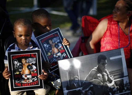 Brandon Liggons, 2, (L) holds an image of Muhammad Ali during the funeral procession for the three-time heavyweight boxing champion in Louisville, Kentucky, U.S., June 10, 2016. REUTERS/Lucy Nicholson