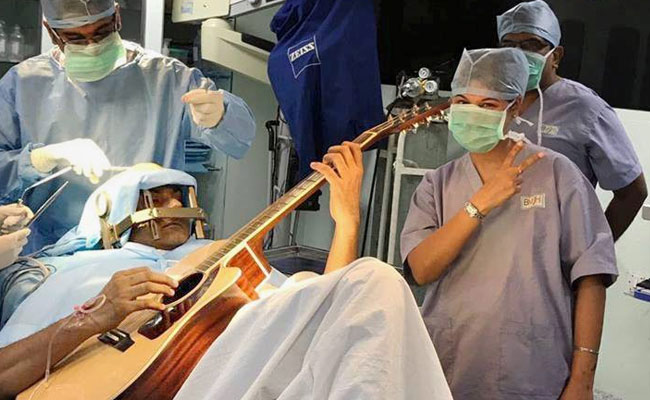 Indian musician plays guitar as doctors perform brain surgery